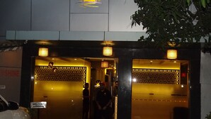 A hotel entrance with a 'Welcome' sign, a sun graphic, and a decorative wall. - Sunshine Hostels (Mumbai)