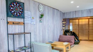 Una habitación con dardos, un reloj, un sofá, una mesa de centro y una estantería.