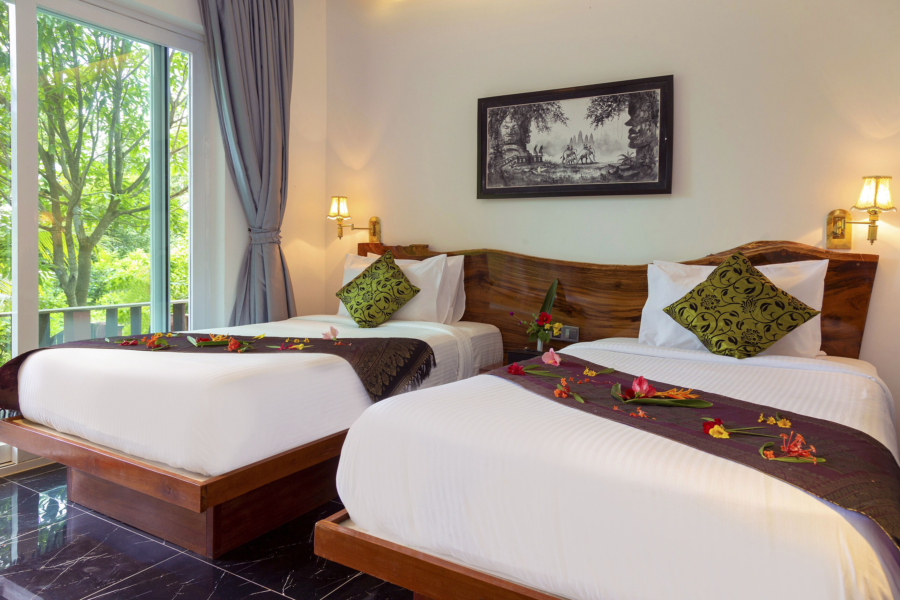 Quarto de hotel com duas camas, uma janela grande com vista para árvores e um quadro na parede.