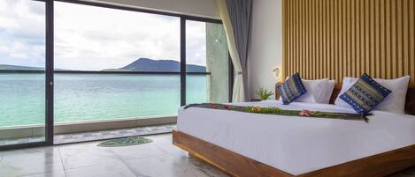 Une chambre avec un grand lit, une vue sur la mer et un mur recouvert de panneaux de bois.