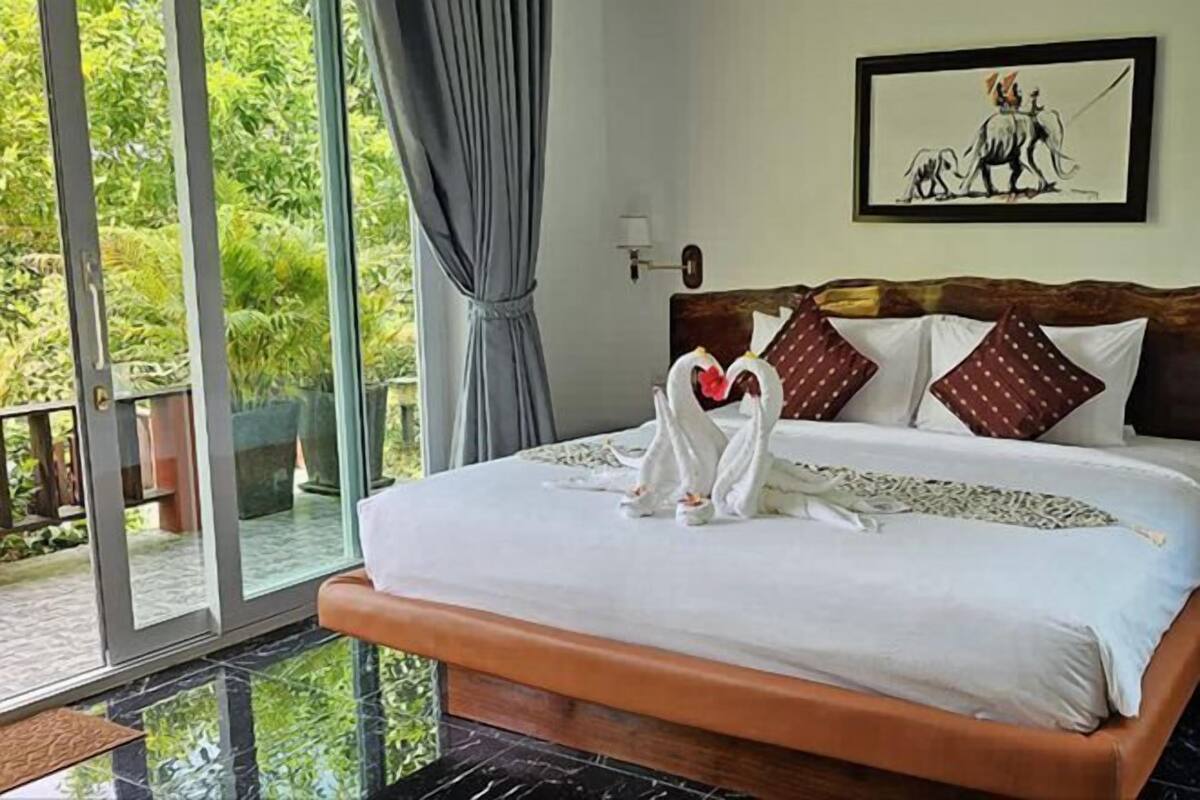 A bed with a wooden headboard, white bedding, and two swan-shaped pillows.