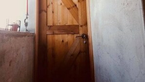 A wooden door with a diagonal pattern, a keyhole, and a light fixture above it. - Kenting Sky Villa (Hengchun)