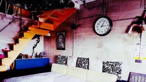 A cozy living room with a sofa, a coffee table, a staircase, and a wall clock. - Kenting Sky Villa (Hengchun)