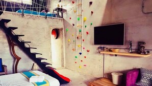 A room with a climbing wall, a bed, a TV, and a couch. - Kenting Sky Villa (Hengchun)