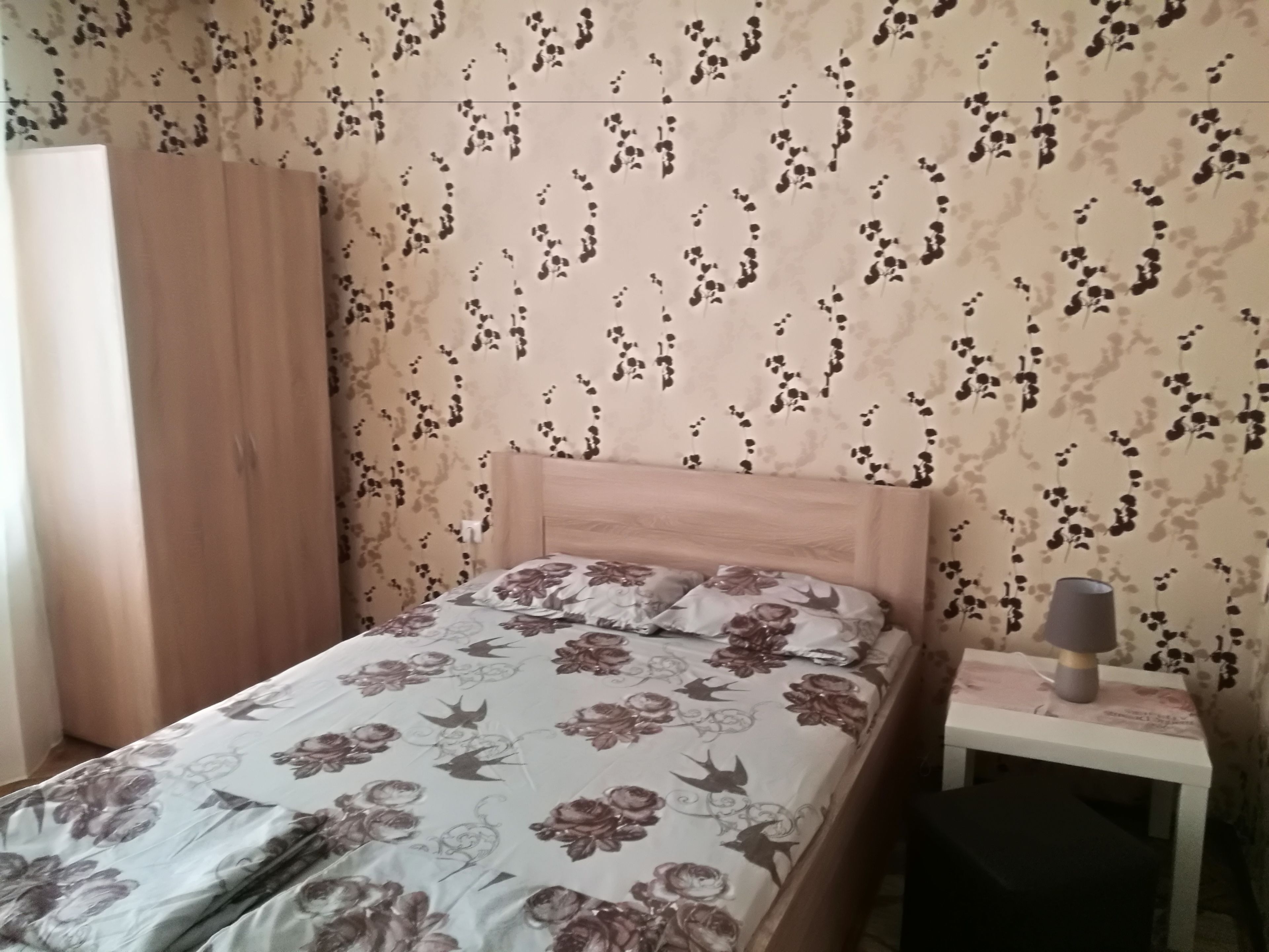 A bedroom with a bed, a nightstand, and a wardrobe.