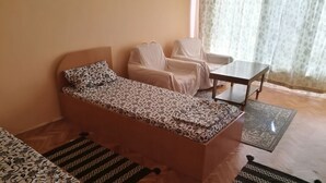 Ein Zimmer mit einer gemusterten Couch, einem Sessel, einem kleinen Tisch und einem Teppich mit Muster.