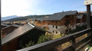 Blick vom Balkon auf eine ländliche Gegend mit traditionellen Holzhäusern und einem Berg im Hintergrund.