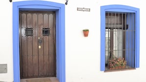A house with a blue-framed door and window, a potted plant, and a sign reading "CASIA AZUL". - Casa Azul (Alozaina)