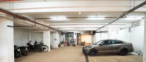 A parking garage with multiple motorcycles and a car parked.