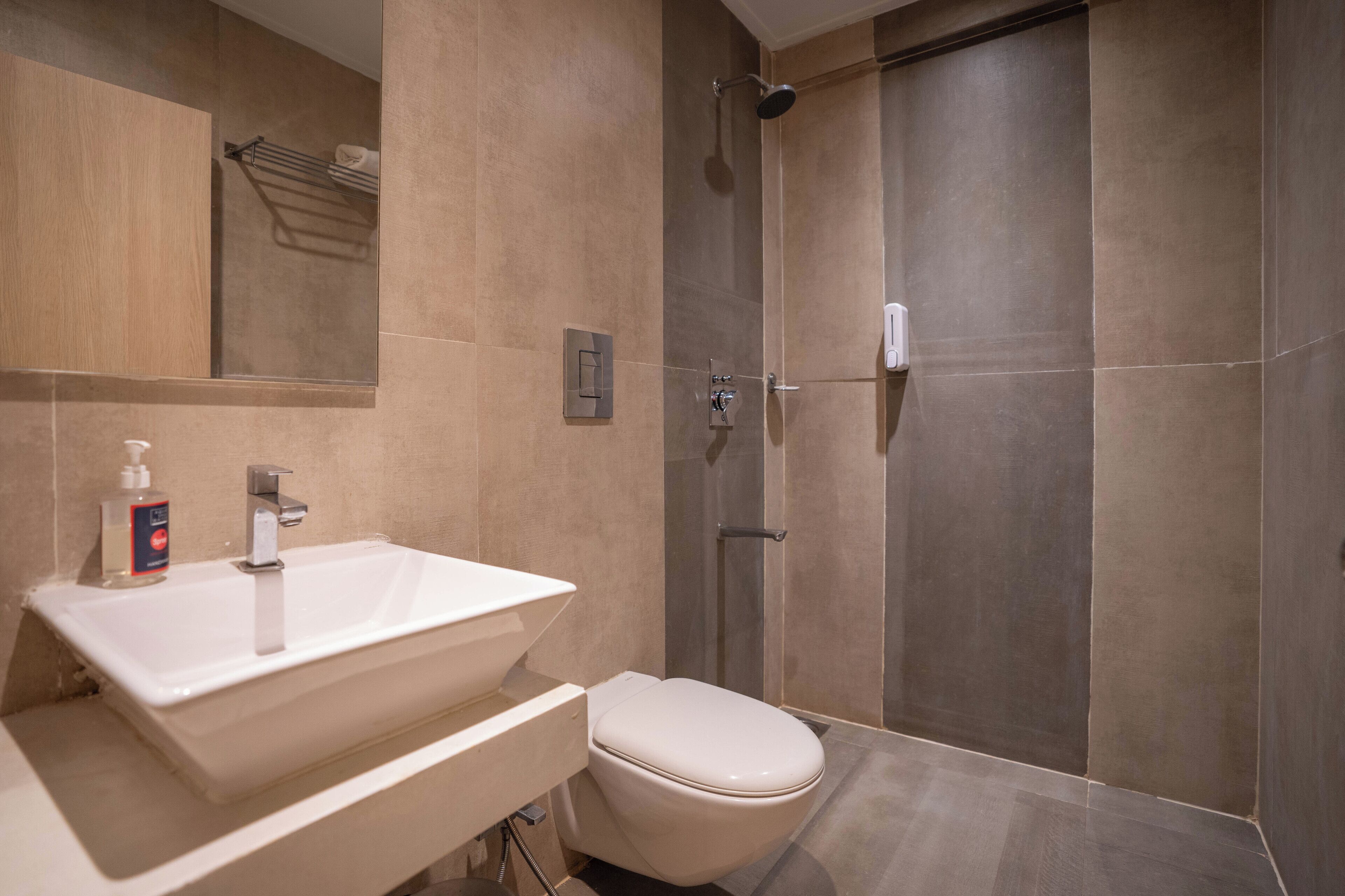 A modern bathroom with a large sink, toilet, and walk-in shower.