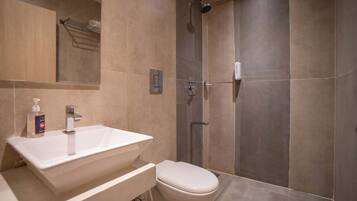 Un baño moderno con un lavamanos grande, inodoro y ducha a ras de suelo.