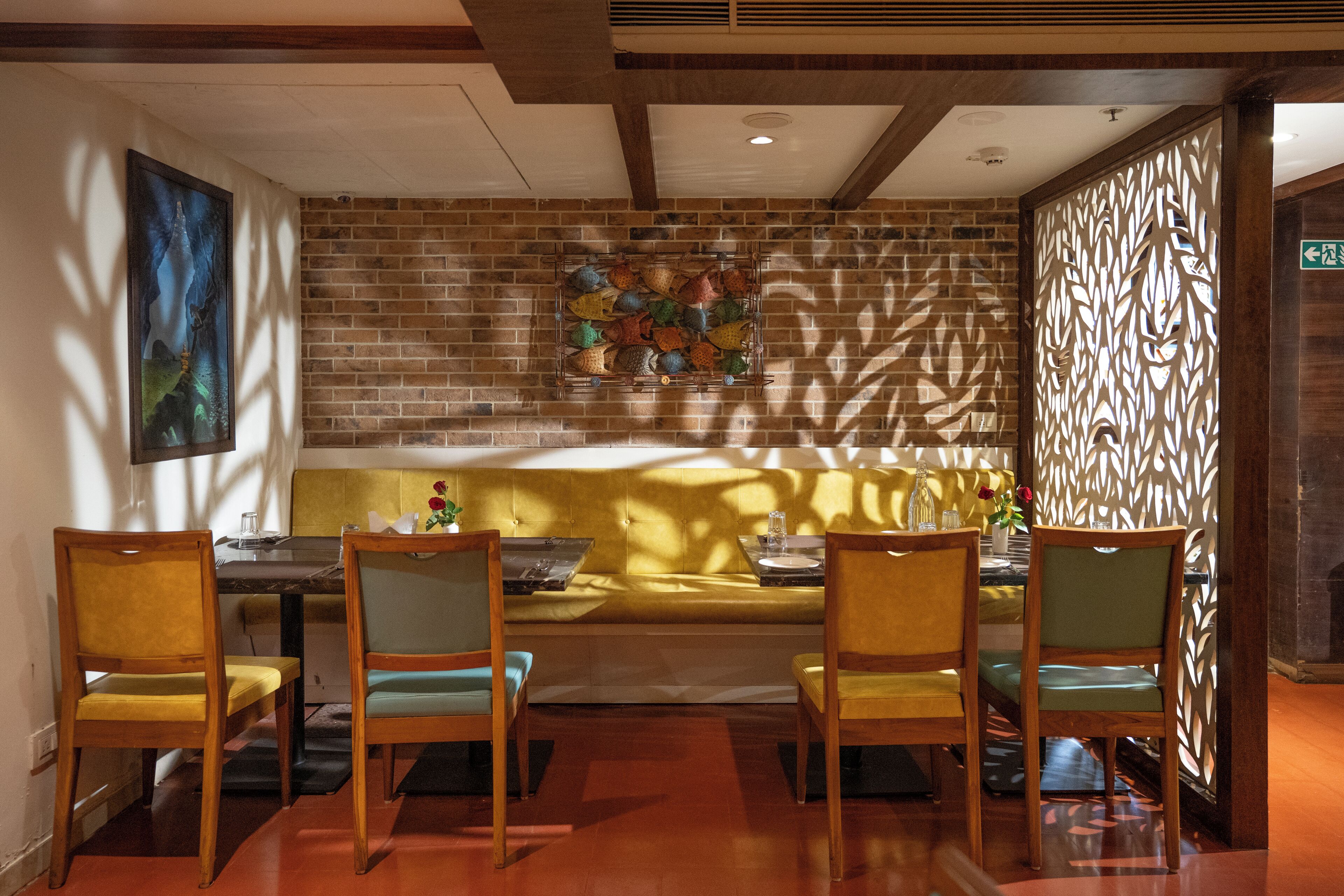 Un comedor con pared de ladrillo, un sofá y sillas de madera.