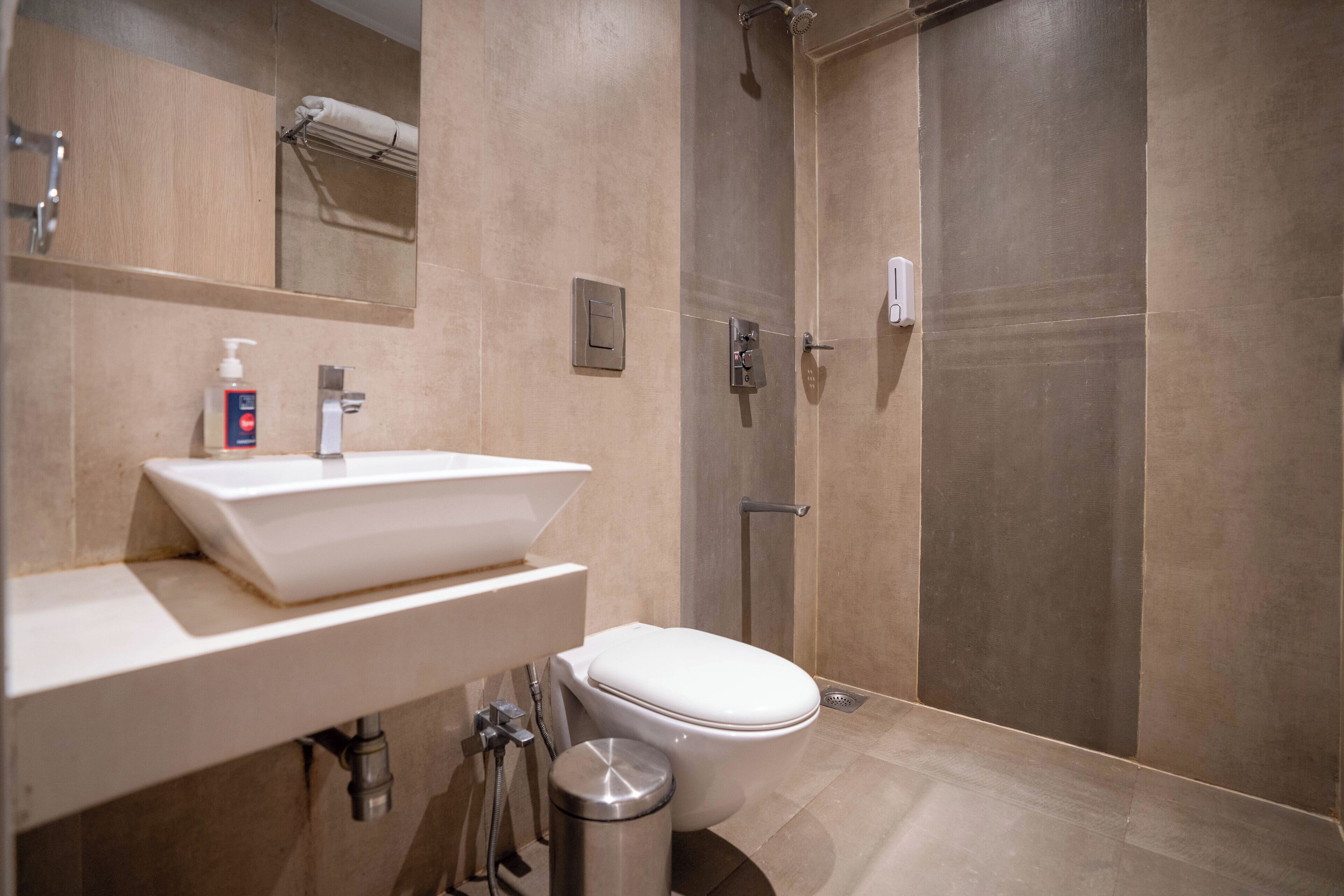 A modern bathroom with a large sink, toilet, and walk-in shower.