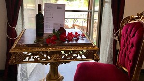 A table with a menu, a bottle of wine, and red flowers. - Royal Rooms Colosseo (Rome)