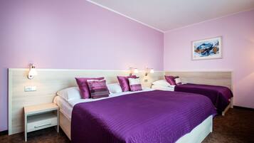 A hotel room with two beds, a nightstand, and a wall-mounted light fixture.
