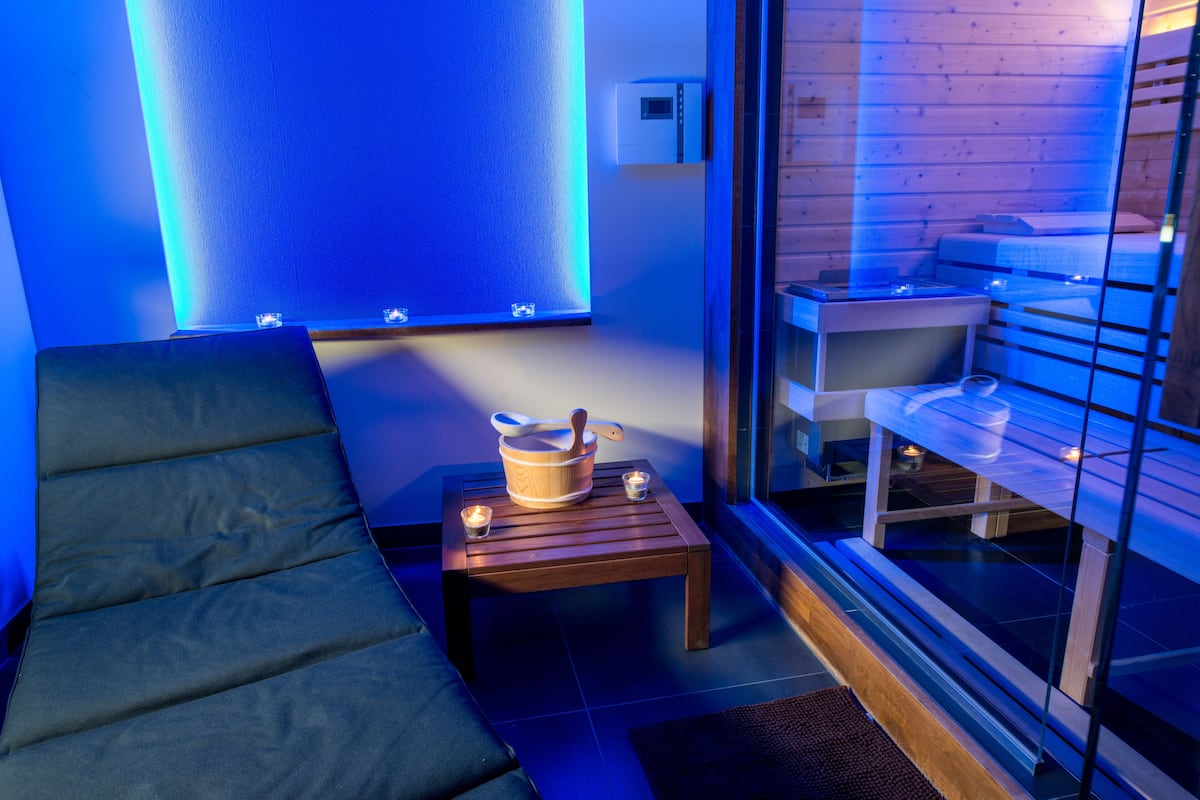 Una habitación moderna con un sofá, una mesa de madera con un cuenco y una cuchara, y un separador de vidrio con una cama y estanterías.