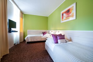 Two beds with white headboards and a large flat-screen TV are featured in this stylish room.