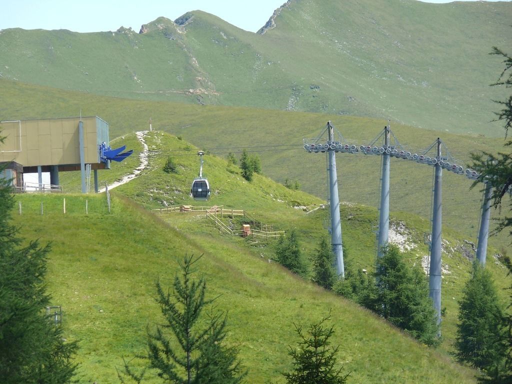 Sistema de teleférico en una zona montañosa, con un edificio y telesilla.