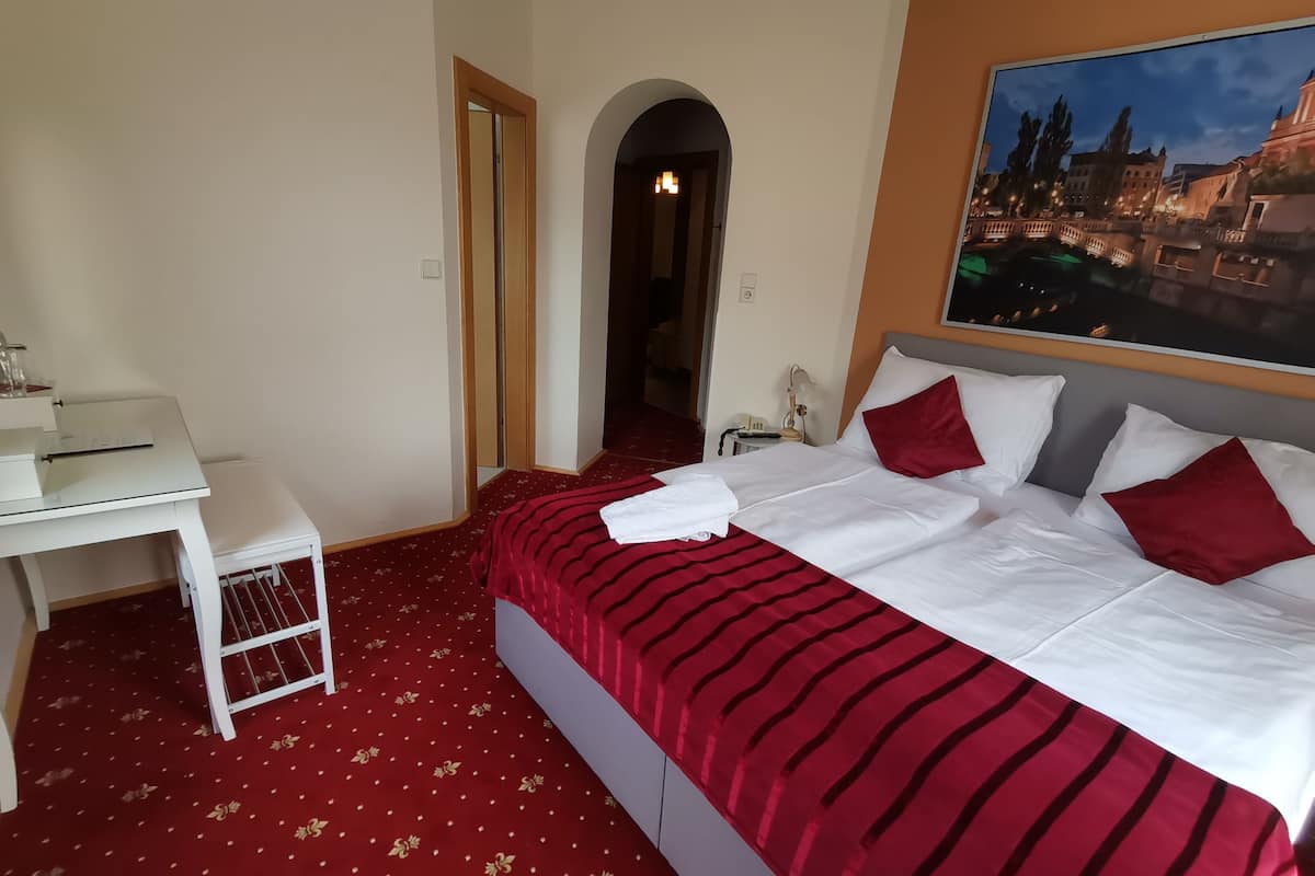 Une chambre d’hôtel avec un lit, un bureau et un tableau représentant un paysage urbain.