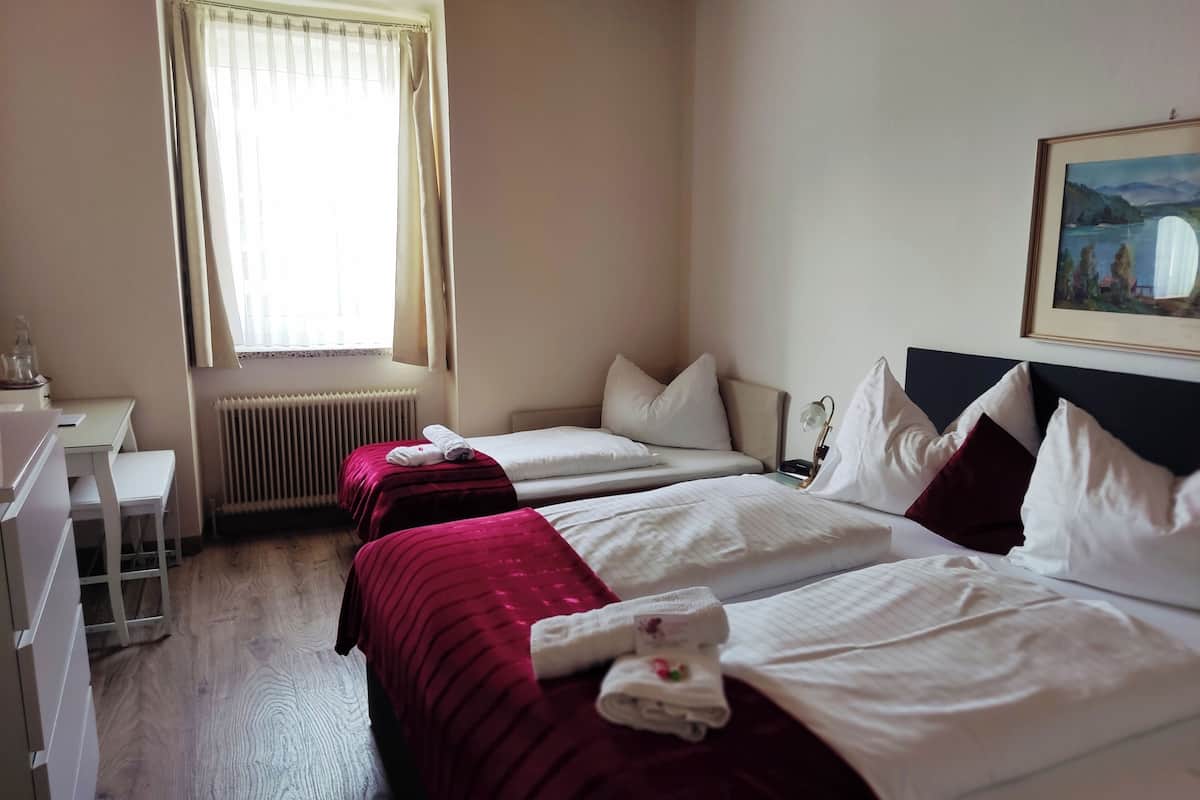 Une chambre d’hôtel avec deux lits, un bureau et un radiateur.