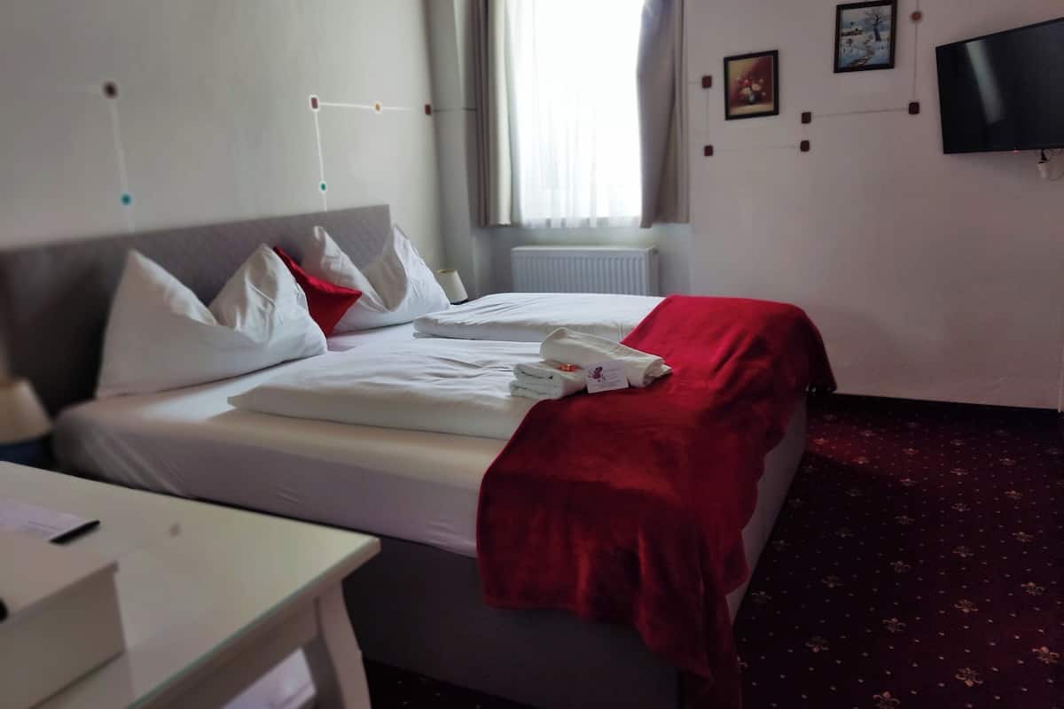 Une chambre d’hôtel avec un lit, un bureau, une télévision et une fenêtre avec des rideaux.