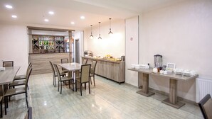 Un espace repas moderne avec une table et des chaises en bois, un comptoir de cuisine avec divers objets et un réfrigérateur.