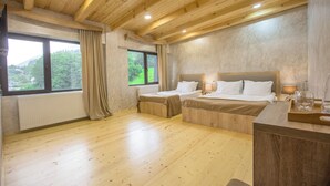 Une pièce avec un plancher en bois, deux lits, une fenêtre avec des rideaux, un radiateur et un plafond en bois.