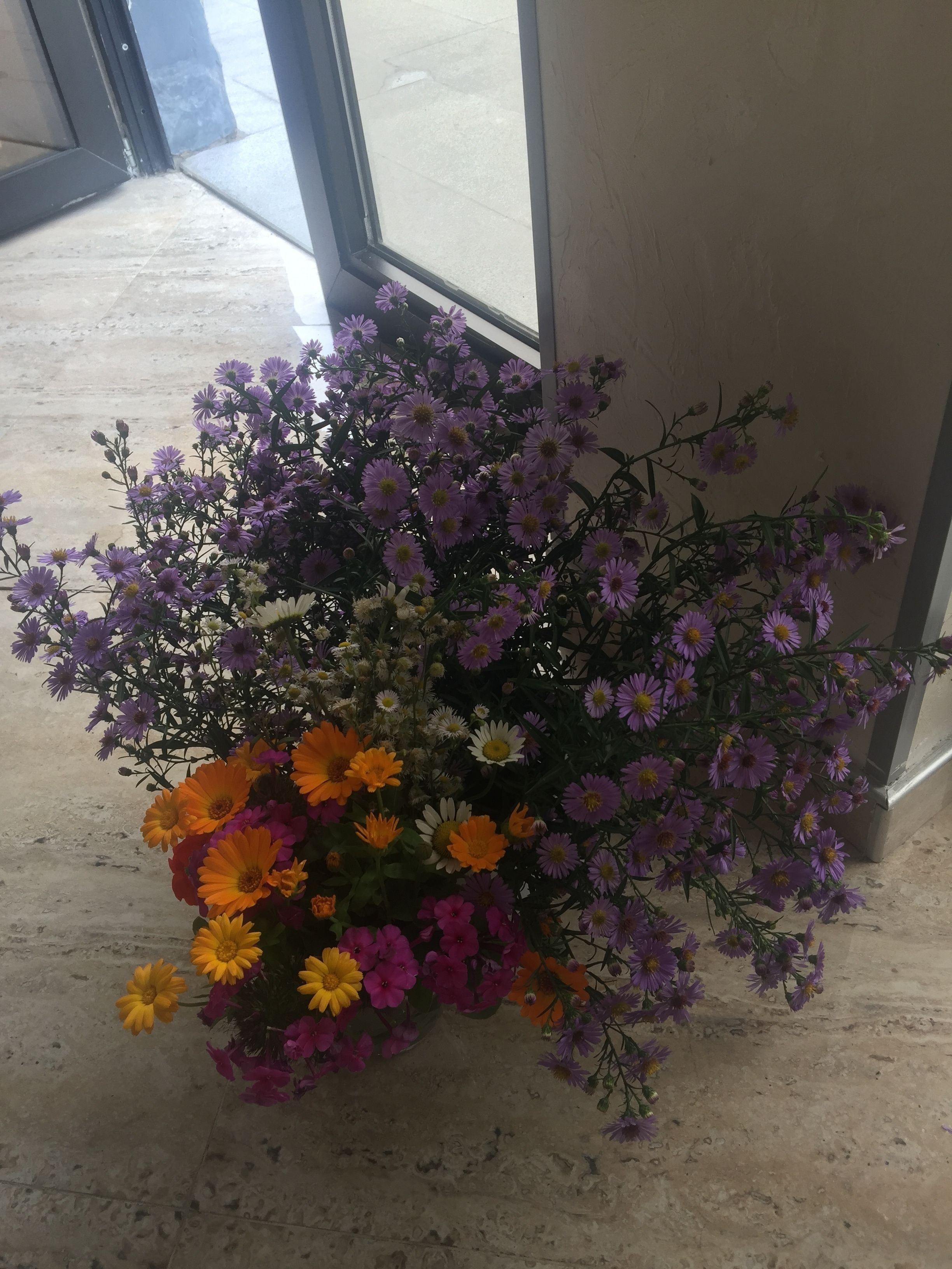 Un ramo de flores en un jarrón sobre un suelo de baldosas.