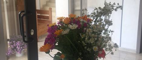 A glass vase with a variety of flowers on a table near a door.