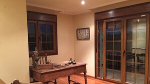 A room with a wooden dining table, chairs, a wooden floor, a window, and a sliding glass door. - O Candil De Santa Ana (Ponte Caldelas)
