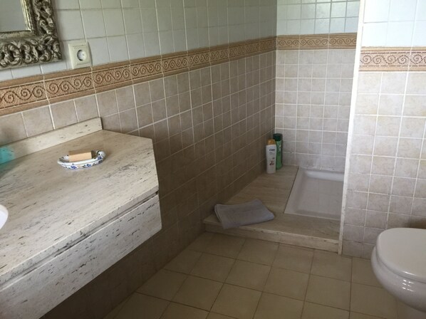 A bathroom with a marble sink, a bathtub, and toiletries on the counter.