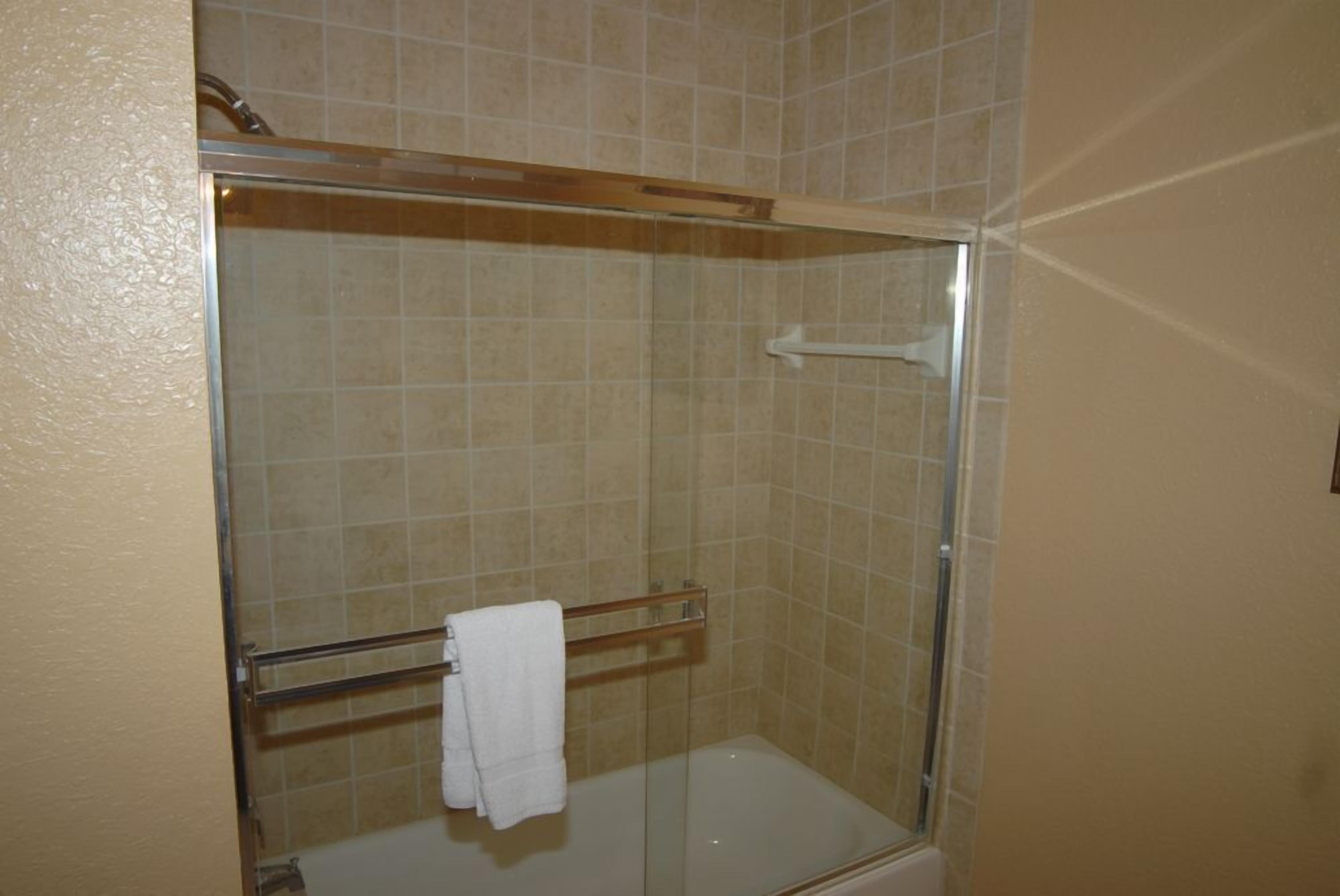 A glass-enclosed shower with a white towel on a rack.