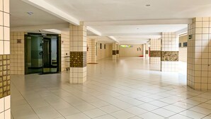 Um corredor amplo e revestido de azulejos, com elevador central, paredes em azulejo e design moderno e limpo.