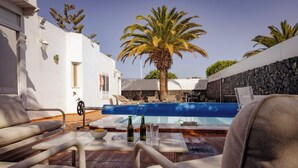 A poolside area with lounge chairs, a table with bottles, and a palm tree.