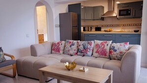 A modern living room with a sofa, a coffee table, and a kitchen in the background.