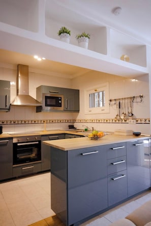 Una cocina moderna con una isla central, horno empotrado, microondas y armarios de acero inoxidable.
