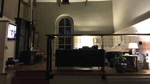 A dimly lit room with a bench, a television, and a window with a view of the outside. - Formerly, Zoar Congregational Chapel offering a unique stay in Pembrokeshire  (Kilgetty)