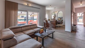 A spacious living area with a large sofa, a dining table with chairs, a kitchen in the background, and a view of the outside. - Beautiful home in Marcana (Marcana)