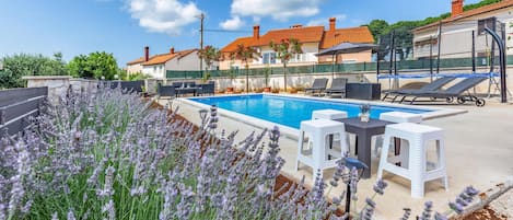 Une piscine avec des chaises longues et un jardin agrémenté de plantes de lavande.