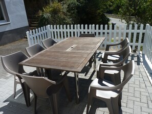 Une terrasse extérieure avec une table en bois et six chaises en plastique.