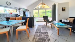 Une cuisine moderne avec un coin repas, un canapé et une vue sur la verdure environnante.