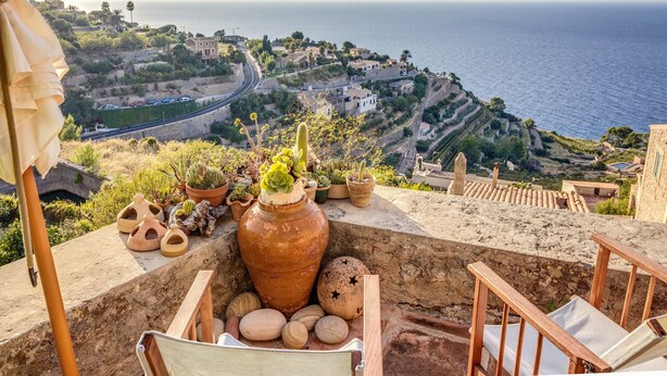 A terrace with a view of the sea, terracotta pots, and a wooden chair. - Vacation Home "Casa Can Sans" with Sea Views (BANYALBUFAR)