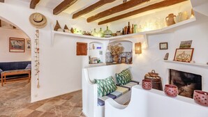 A cozy room with a white sofa, a fireplace, and shelves with various decorative items. - Vacation Home "Casa Can Sans" with Sea Views (BANYALBUFAR)