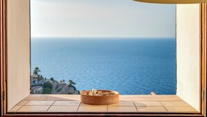 A window with a view of the sea, a bowl on the windowsill, and a tiled floor. - Vacation Home "Casa Can Sans" with Sea Views (BANYALBUFAR)