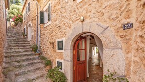A narrow stone staircase leading to a building with a wooden door and a number plaque. - Vacation Home "Casa Can Sans" with Sea Views (BANYALBUFAR)