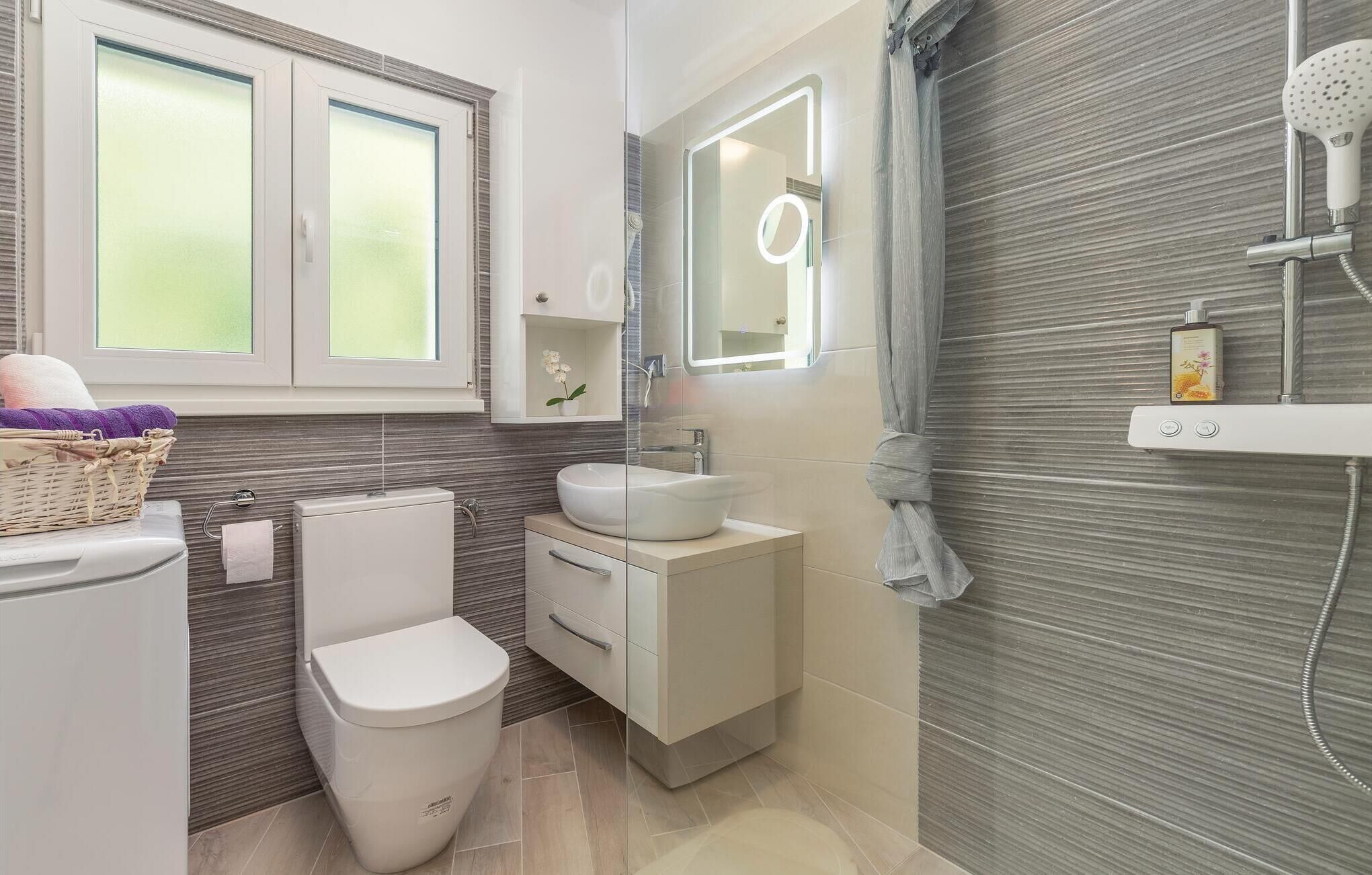 A modern bathroom with a toilet, sink, and shower.