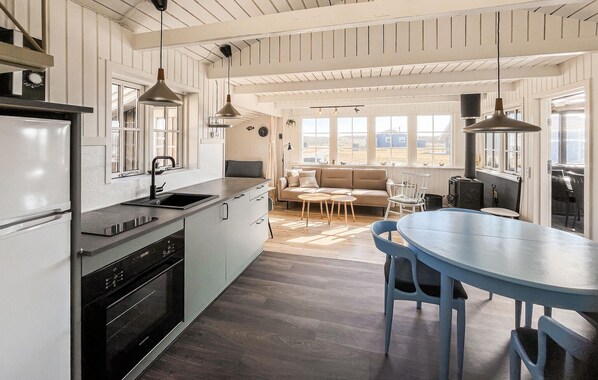 Une cuisine moderne dotée d’un four encastré, d’un évier et de luminaires suspendus.