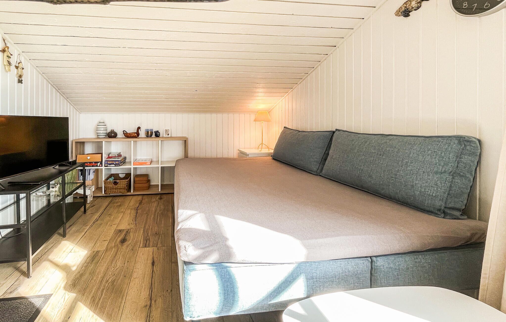 Una stanza con un letto, una TV, uno scaffale con diversi oggetti e una lampada.