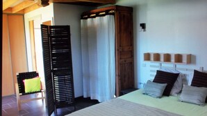 A bedroom with a bed, a wooden wardrobe, a window with curtains, and a shelf with books. - Maisonette classified ***, in the heart of the greenery, between ocean and Landes forest (Saint-Julien-En-Born)