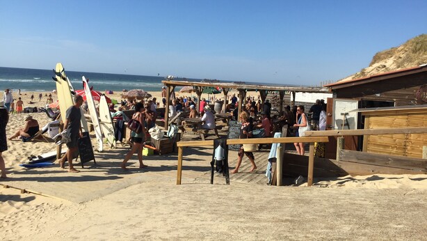 A crowded beach with people and surfboards, a wooden structure, and a clear blue sky. - Maisonette classified ***, in the heart of the greenery, between ocean and Landes forest (Saint-Julien-En-Born)